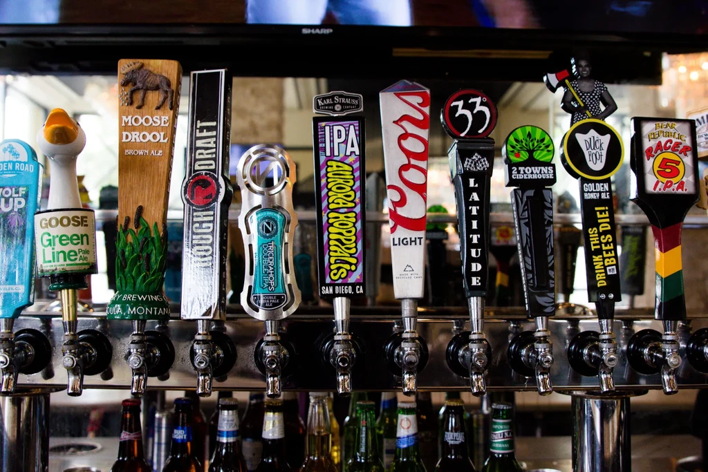 Ten distinct beer and cider taps displayed at a bar.