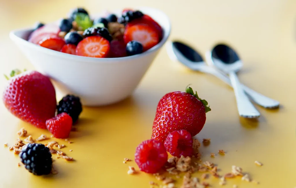 Close-up of a fruit and granola bowl with scattered berries.