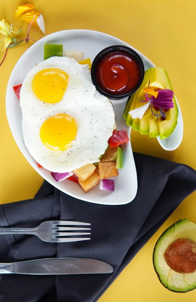 Breakfast plate with sunny-side-up eggs, roasted potatoes, and avocado.