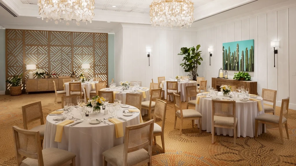 Bright, elegant dining room with set tables and ornate chandeliers.