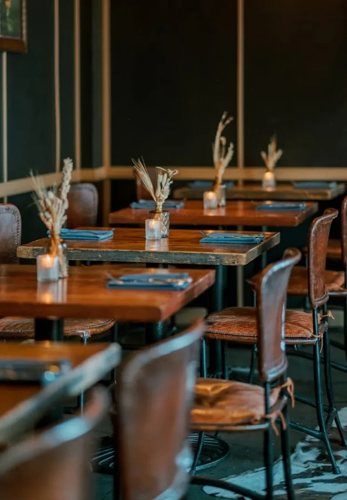 Rustic-chic restaurant interior with wooden tables and botanical centerpieces.