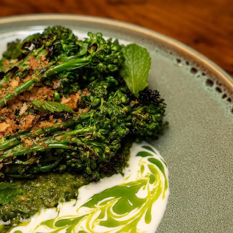 Charred broccolini with two sauces, crispy crumbs, and a mint leaf.