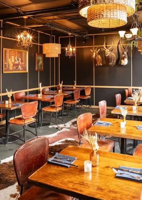 Restaurant dining room with cowhide floor, taxidermy, and ornate chandeliers.