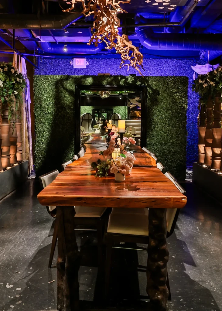 Dimly lit restaurant with rustic table, green wall, and blue light.