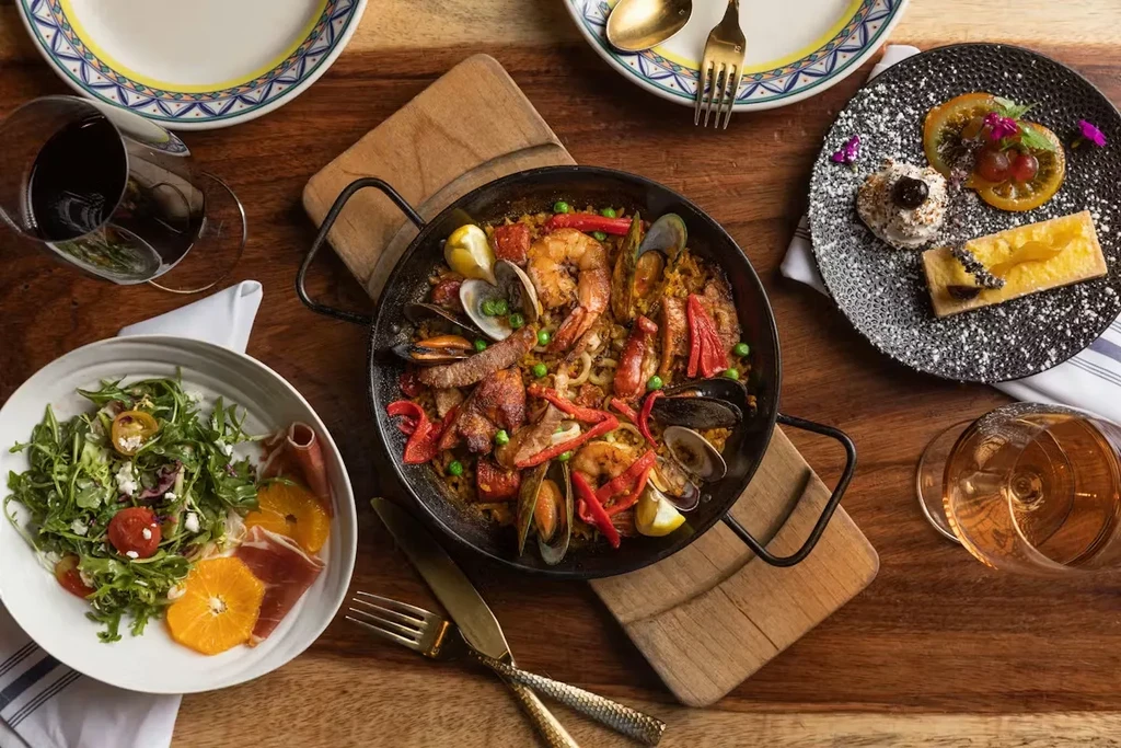 Overhead: Vibrant paella, salad, and desserts on a generously set table.