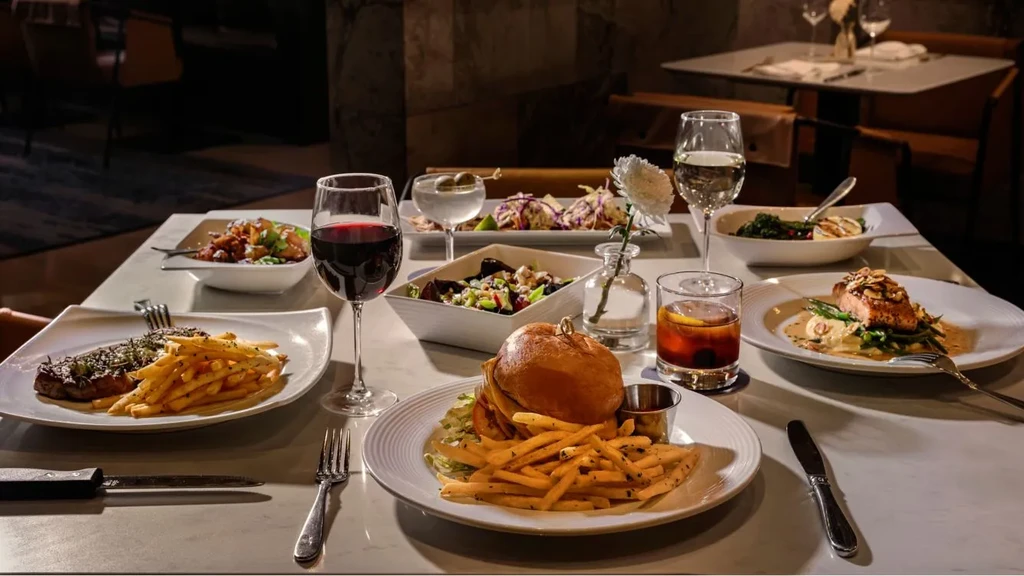 Elegant restaurant table filled with steak, salmon, burgers, salads, and drinks.