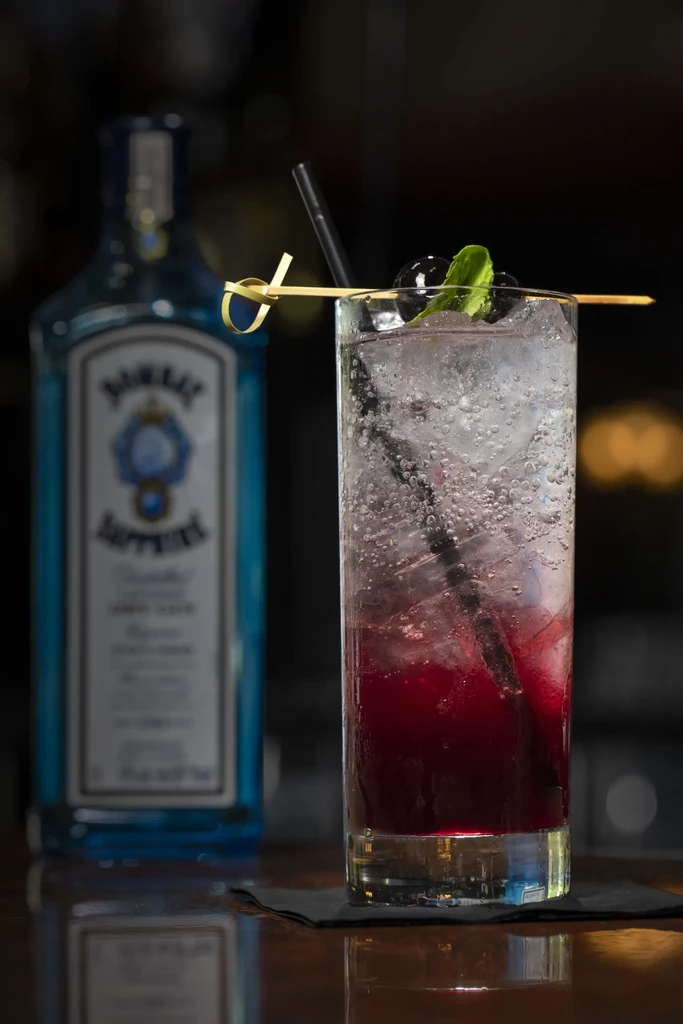 Layered red and clear cocktail with berries, mint, and Bombay Sapphire gin.