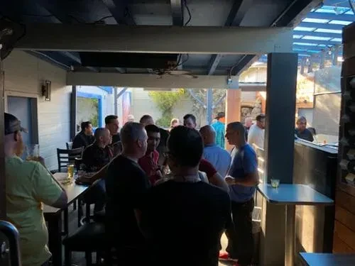 Lively indoor-outdoor bar patio filled with socializing people.