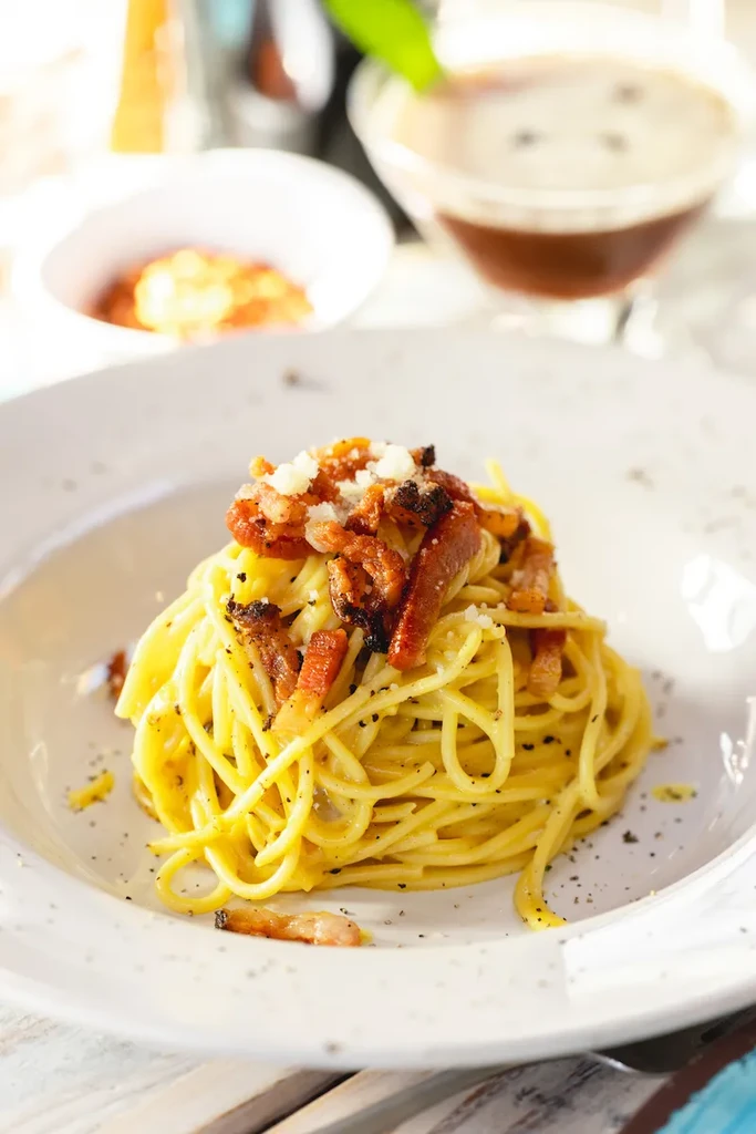 Plate of creamy spaghetti carbonara with guanciale, cheese, and pepper.