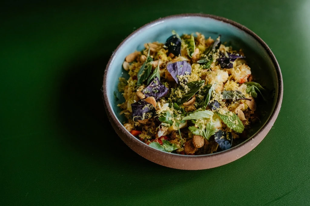 Rustic bowl of vibrant grain salad with nuts, herbs, and purple basil.