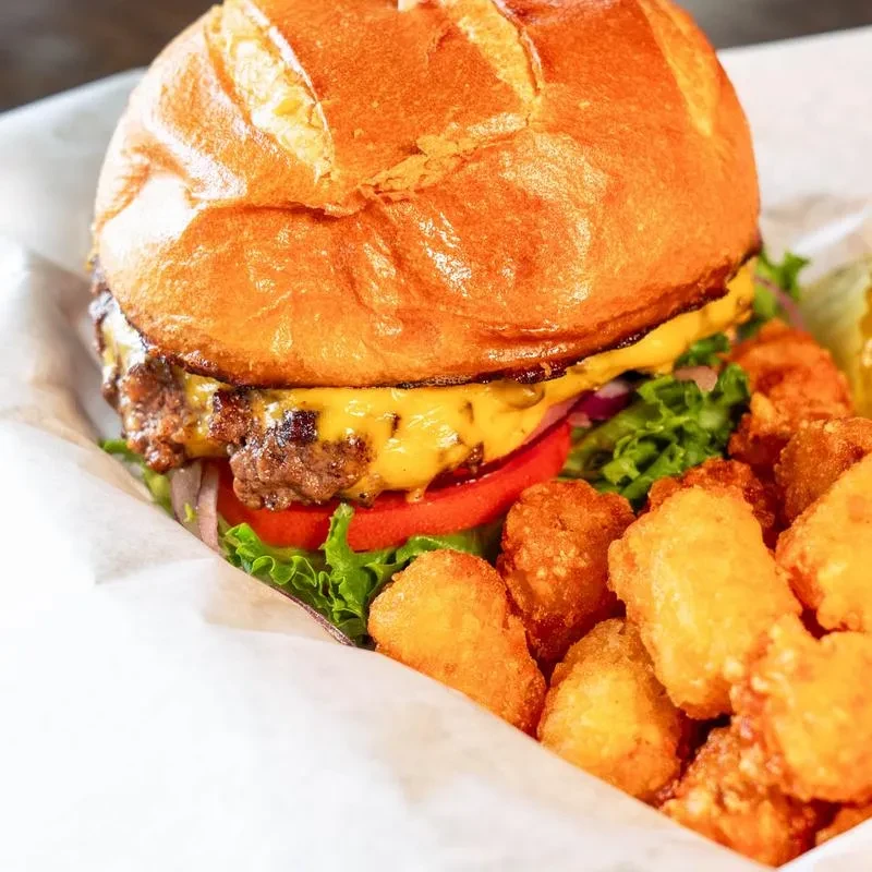 Cheeseburger with melted cheese, vegetables, and crispy tater tots.
