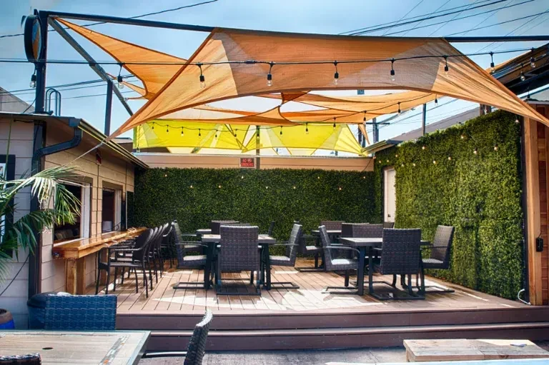 Empty multi-level outdoor dining area with fabric shades and bar.