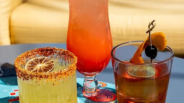 Three unique cocktails: spiced rim, vibrant gradient, and amber with orange peel.