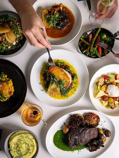 Overhead view of a dining table with multiple gourmet dishes and drinks.