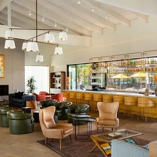 Modern bar lounge with varied seating, well-stocked bar, and patio view.