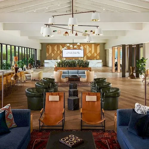 Modern lounge with vaulted ceiling, large chandelier, and multiple seating areas.