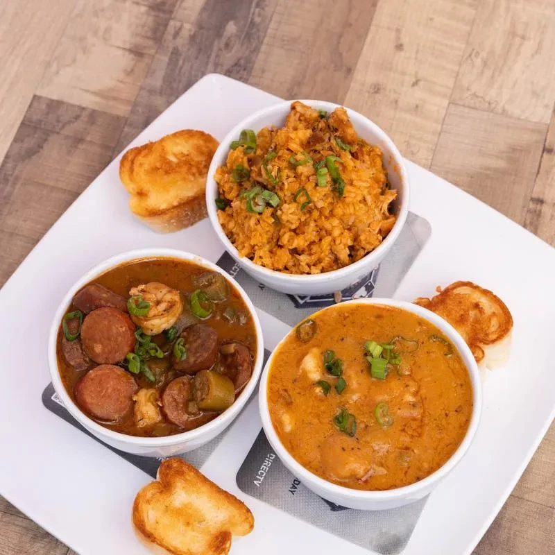 Three bowls of jambalaya, gumbo, and shrimp étouffée with bread.