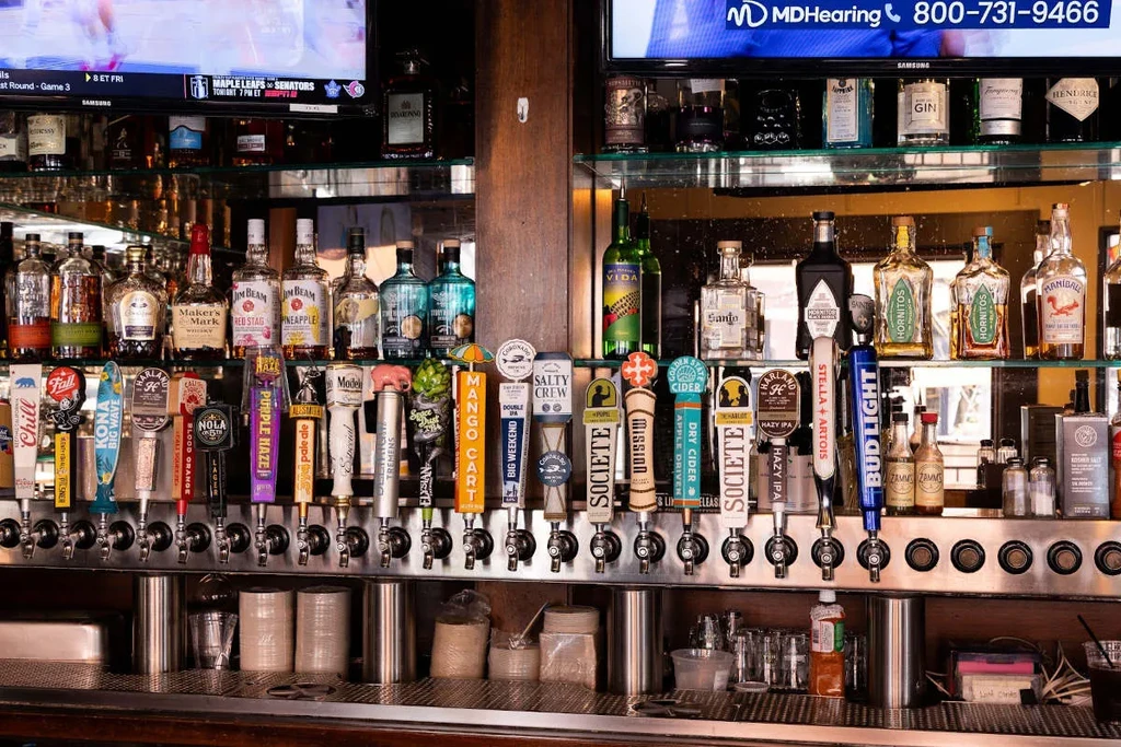 Detailed bar view: numerous beer taps, diverse liquor, and background TVs.