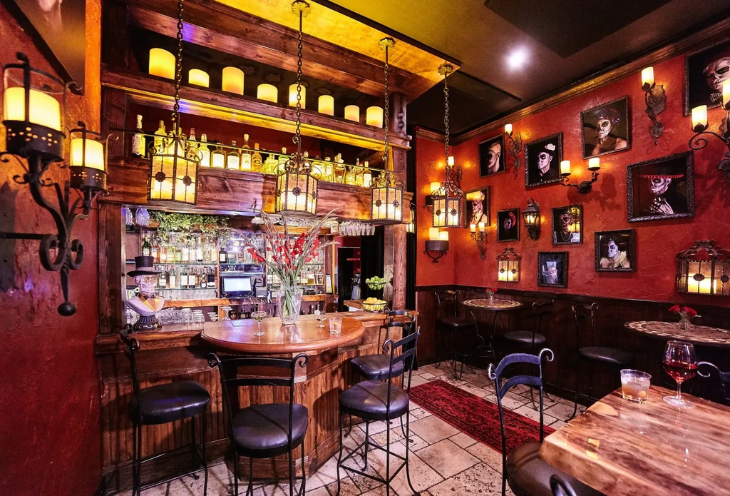 Atmospheric bar with red walls, wooden bar, and sugar skull art.