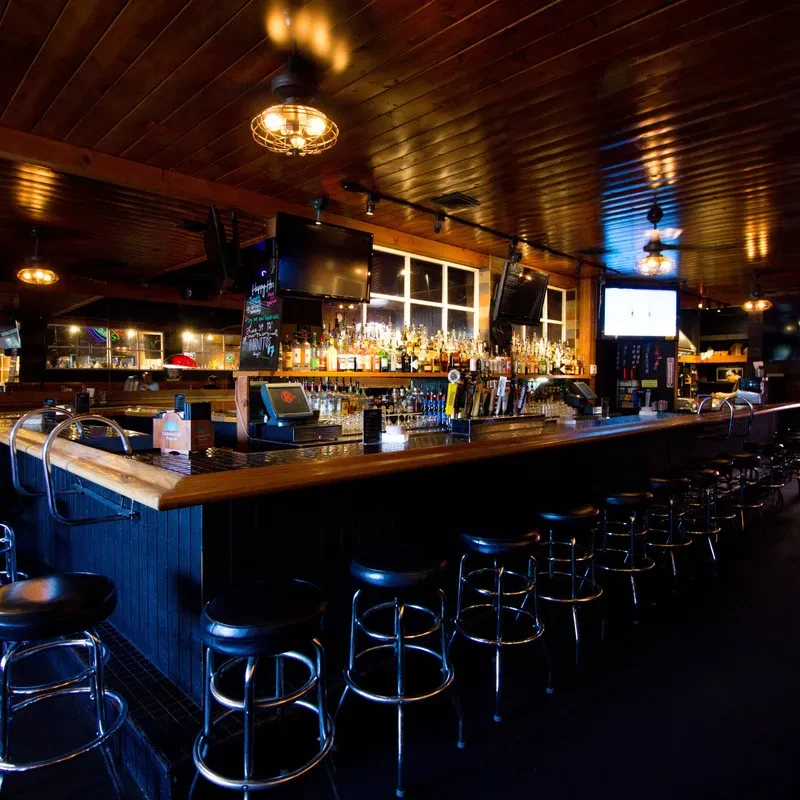 Long, dark wooden bar in a warm, classic pub setting.