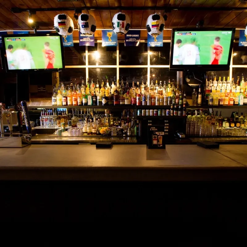 Sports bar with liquor bottles, TVs showing soccer, World Cup banners.