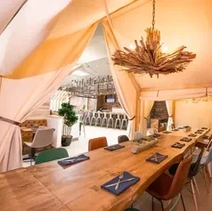 Restaurant dining area with fabric tent, wood table, and branch chandelier.