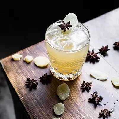 Cocktail in cut-glass tumbler, garnished with candied ginger and star anise.