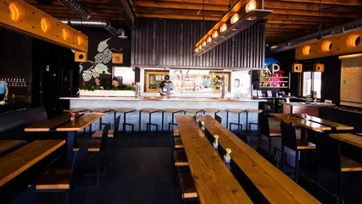 Modern industrial brewery with communal tables, concrete bar, and hops decor.