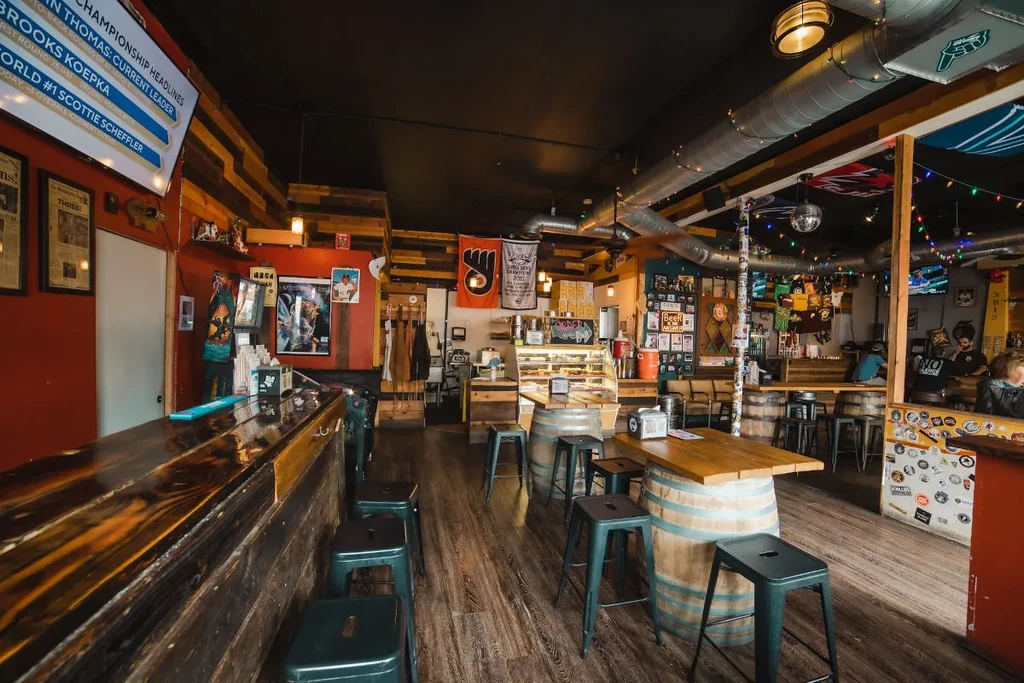 Lively, eclectic bar interior with dark wood, red wall, and industrial decor.
