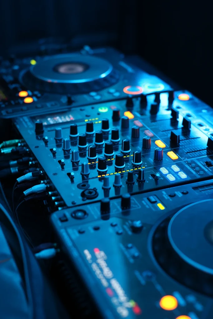 Professional DJ turntables and mixer illuminated by blue and orange lights.