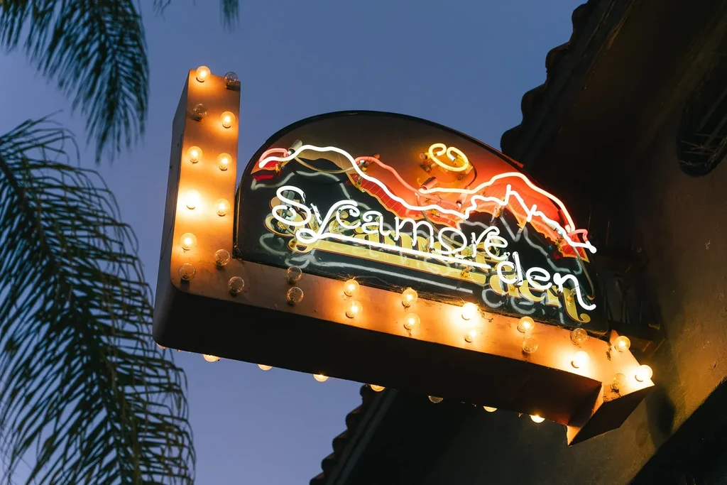 Sycamore Garden's classic marquis sign with neon and bulb lights at night.