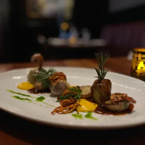 Meticulously plated gourmet dish with protein, potatoes, and sauces.