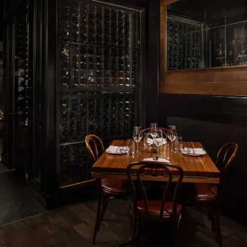 Sophisticated restaurant with a beautifully set table and extensive wine wall.