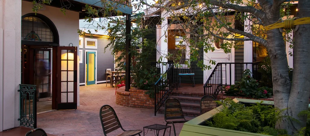 Empty outdoor restaurant patio with tables, chairs, and warm string lights.