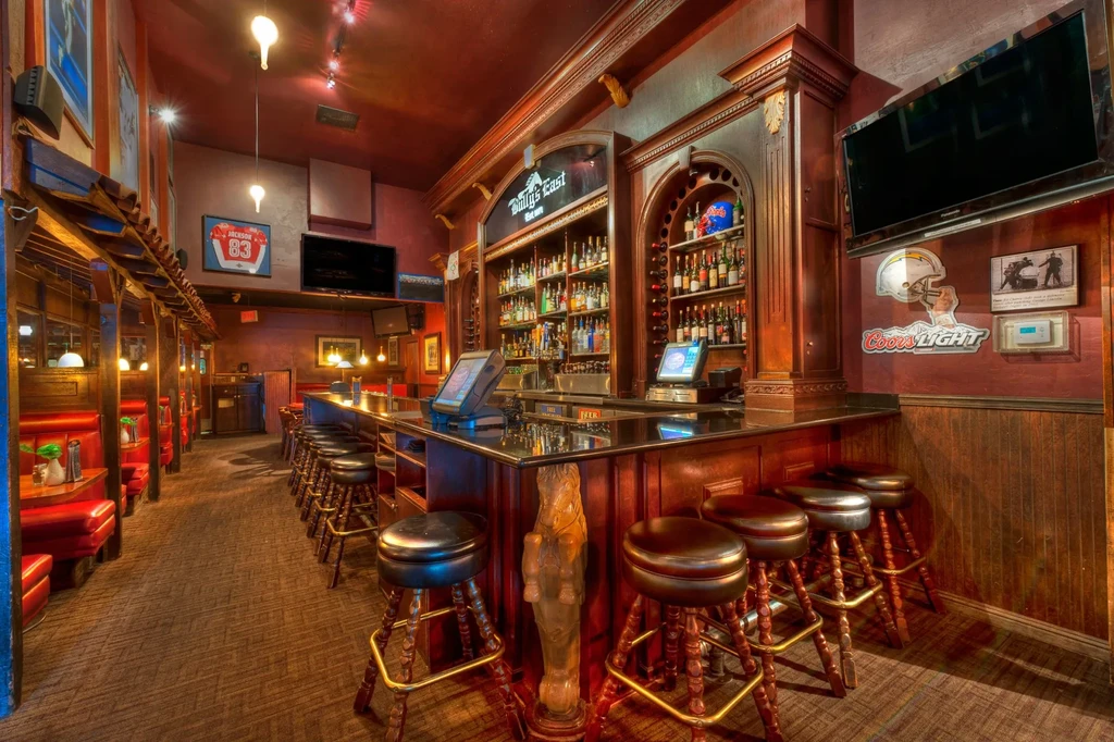 Sully's East sports bar interior with a stocked bar and red booths.