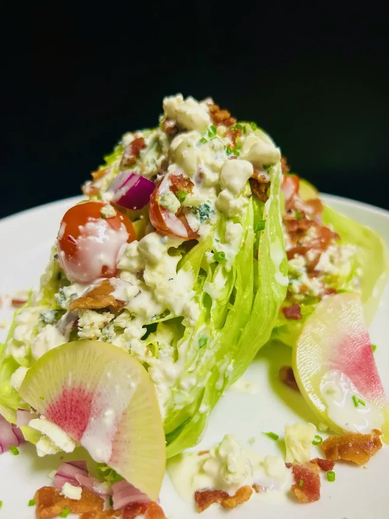 Iceberg wedge salad with blue cheese, bacon, tomatoes, and watermelon radish.