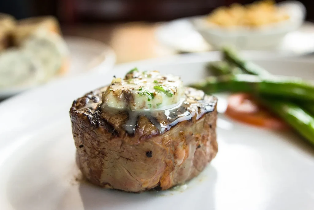 Close-up of a grilled steak with melting herb butter and asparagus.