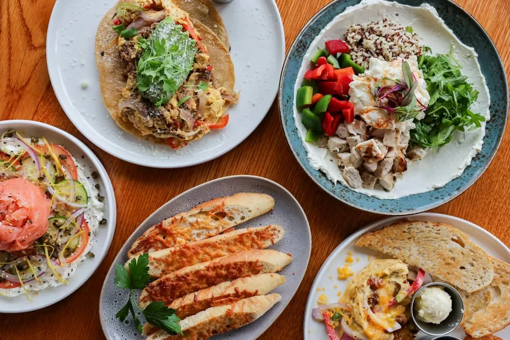 Top-down view of five diverse savory breakfast dishes on a wooden table.