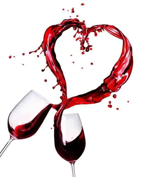 Red wine forms a heart-shaped splash between two wine glasses.