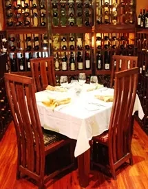 Set dining table for four, framed by wooden wine racks.