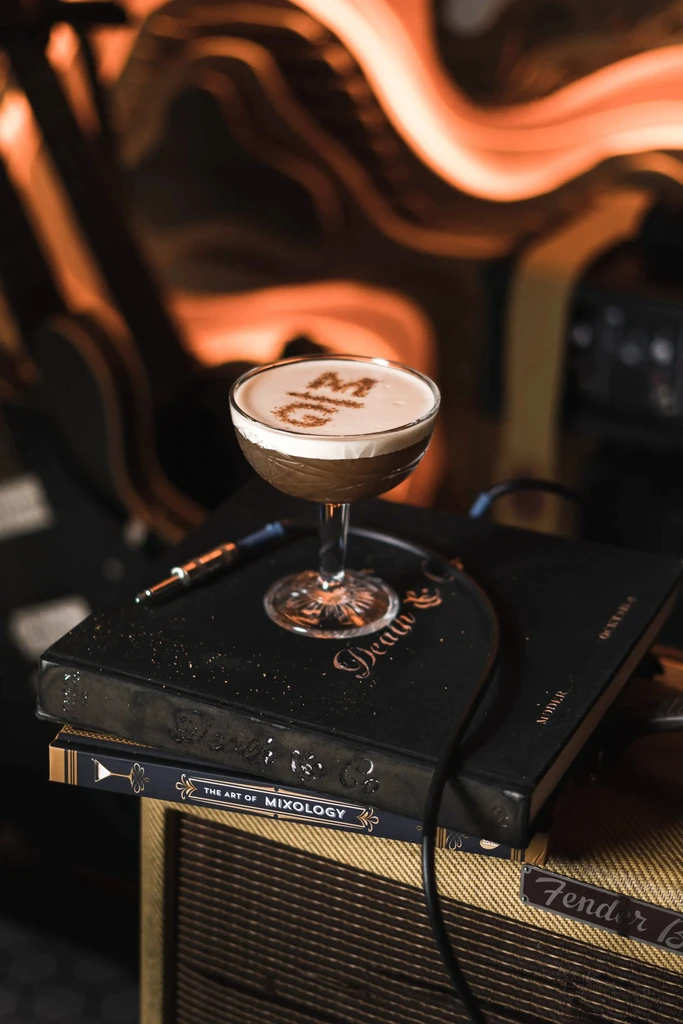 Dark cocktail with 'MG' dusted foam, on books and amplifier.