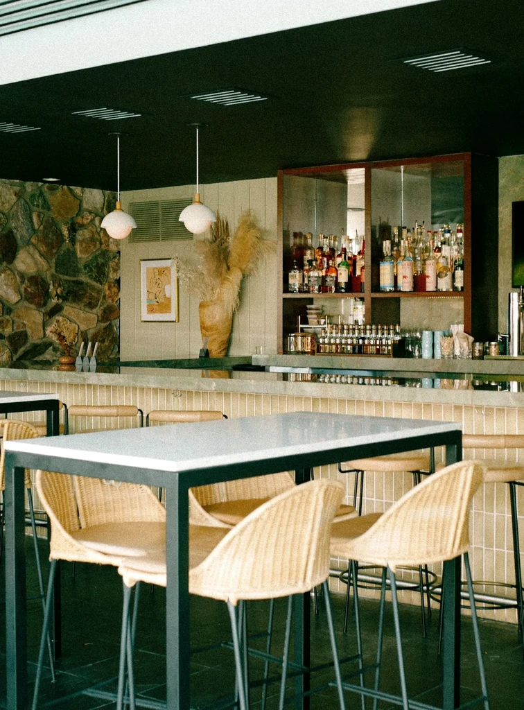 Modern empty restaurant bar with high-top table and varied wall textures.