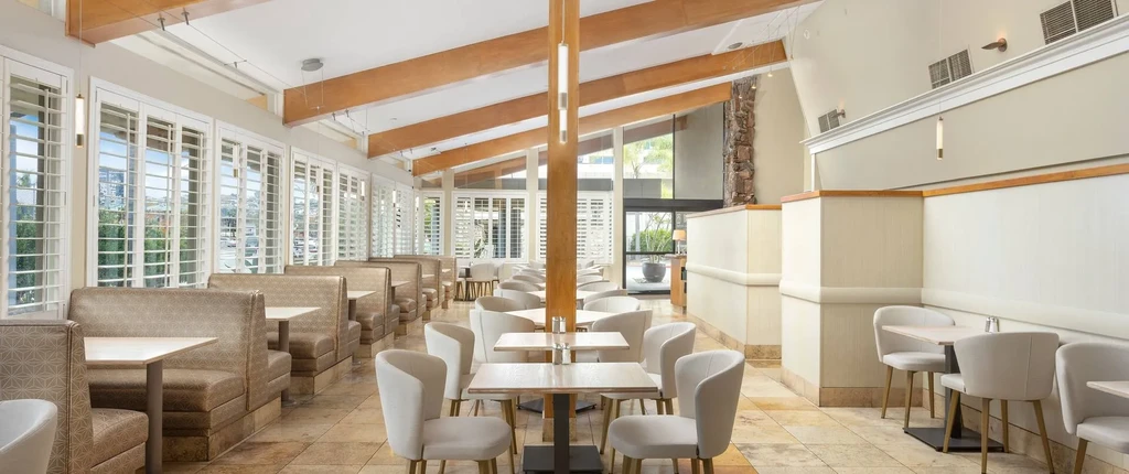 Bright, empty restaurant interior featuring booth seating, tables, and windows.