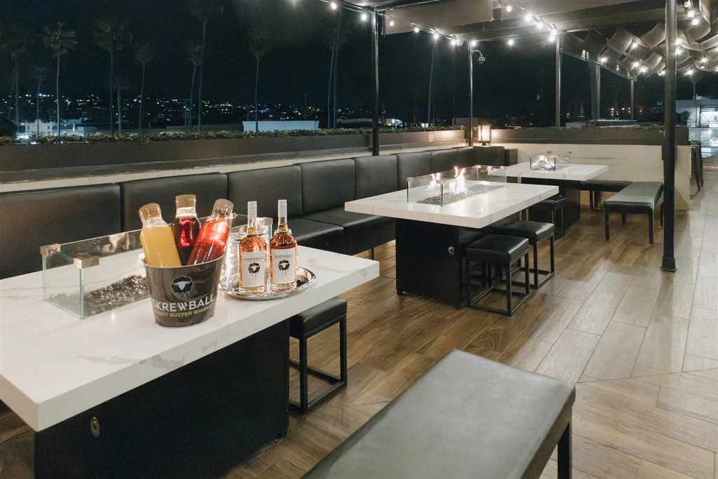 Rooftop bar with fire pits, Screwball Whiskey, and city lights.