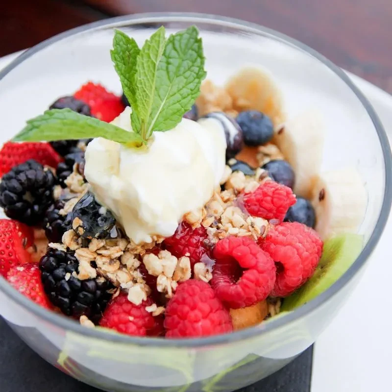 Fruit and yogurt parfait with berries, banana, kiwi, granola, mint.