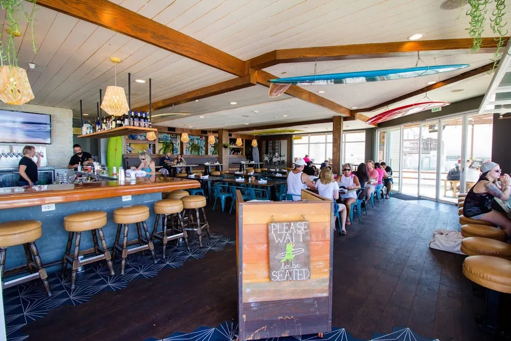 Lively surf-themed restaurant interior with bar, dining, and patrons.