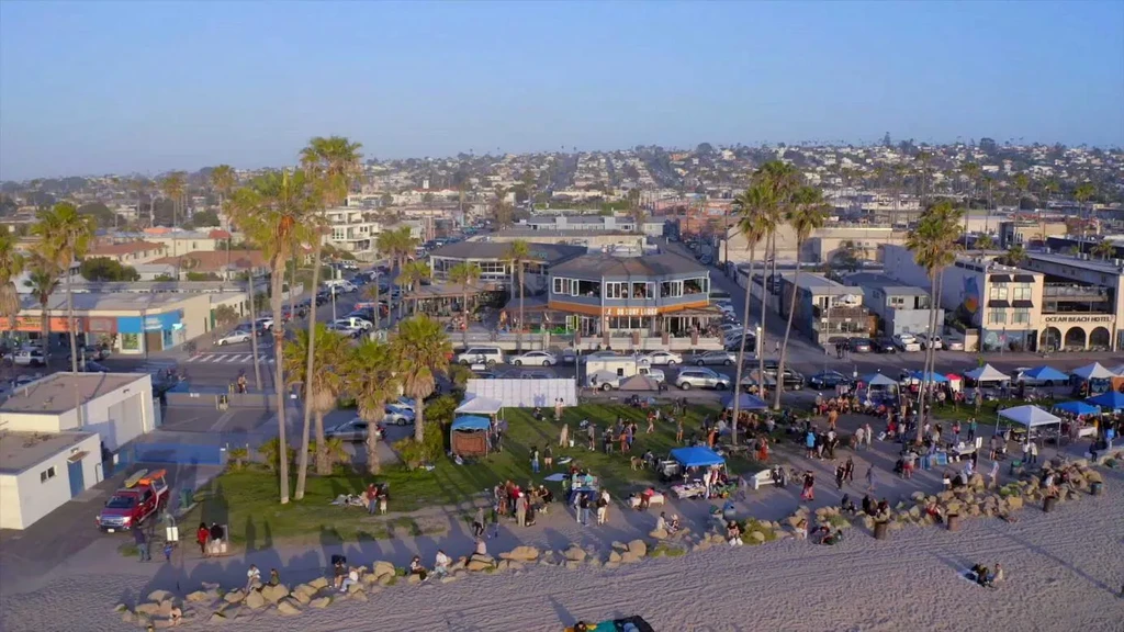 Aerial view: coastal town with surf lodge, hotel, beach, and event.