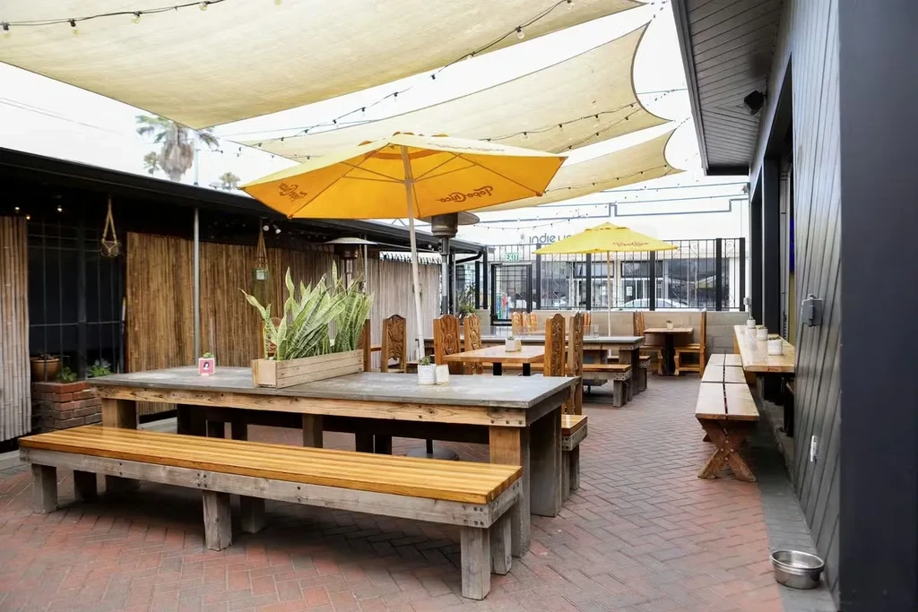 Empty rustic outdoor patio with brick floor, string lights, and dog bowl.