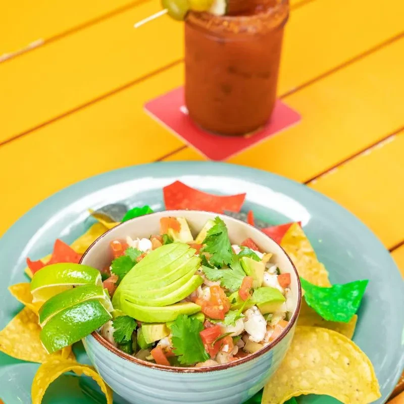 Top-down view of vibrant ceviche, colorful chips, and a garnished drink.