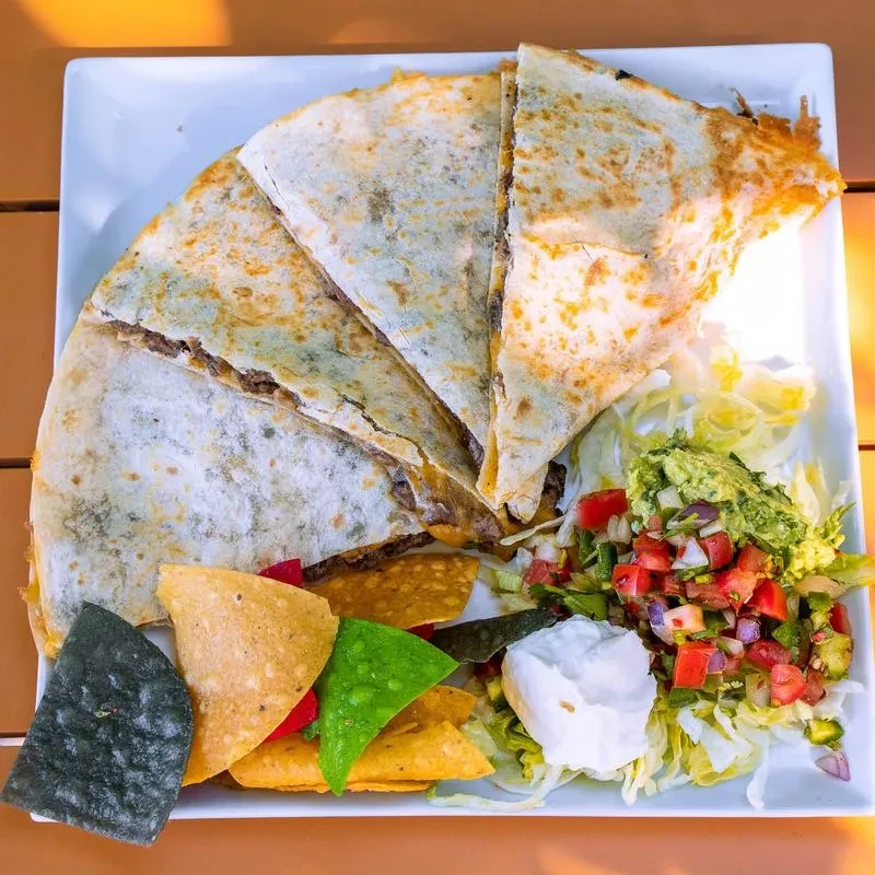 Overhead view of a quesadilla meal with guacamole, salsa, and chips.